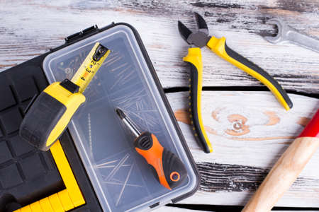 Tool box, pliers, screwdriver, hammer and ruler. Kit of construction tools and instruments on wood...