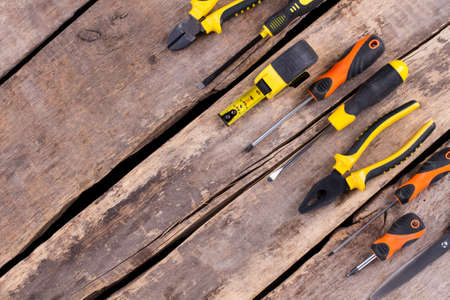 Construction tools on cracked wooden boards background. Set of screwdrivers and pliers on rustic...