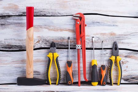 Set of construction tools on wooden background. Hammer, pliers, screwdrivers and an adjustable...