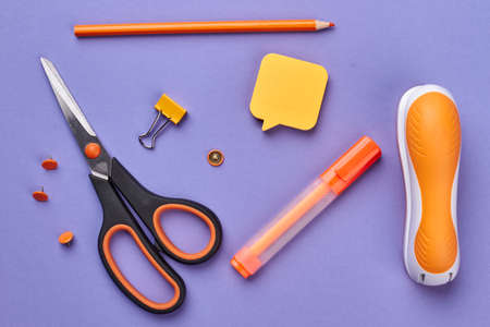 School supplies on purple background. Scissors, marker, stapler and sticky note on color background....