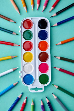 Watercolor painting supplies, top view. Creative flat lay with watercolor palette and multicolored pencils on color background.の写真素材