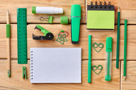 Blank notebook and office supplies. Flat lay of green school or office accessories on wooden table. Education concept.の写真素材