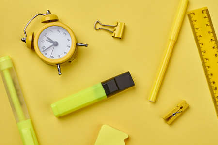 Alarm clock and school supplies on yellow background. Set of stationery accessories. Concept of education.の写真素材