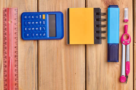 School supplies on desk background with copy space. Blank spiral notebook, calculator and other...