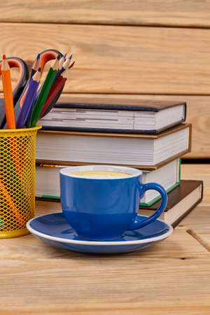 Books, pencils and coffee cup. Office desk with stack of books, pencils in holder and cup of coffee.の写真素材