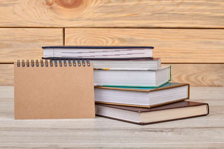 Notepad and books on wooden background. Stack of books with notepad on wooden background. Back to school concept.の写真素材