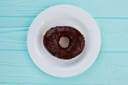 Delicious chocolate donut on plate. Yummy cake on white plate, top view.