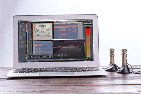 Laptop and stereo record microphones. Opened laptop on wooden table. Modern technology concept.の写真素材