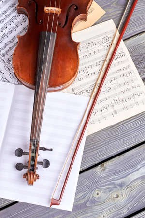 Violin and musical notes, top view. String musical instrument and bow on old wooden background. Classical musical background.の写真素材