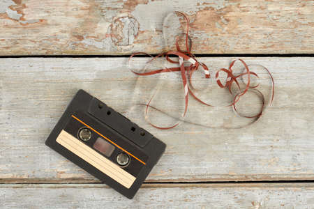 Old black audio cassette tape. Compact cassette with clipping path on rustic wooden background.の写真素材