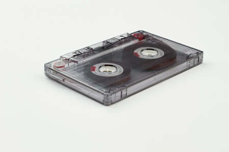 Compact cassette . Transparent audio tape over white background. Old-fashioned musical object.