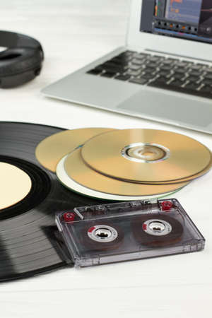 Vinyl record, compact disc and cassette. Vinyl plate, CD disks, audio tape cassette, laptop and...