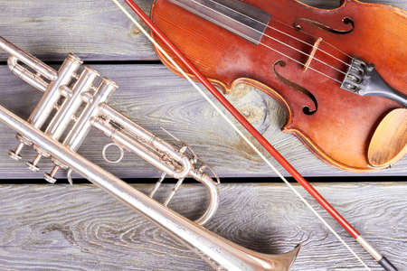 Vintage style musical instuments. Old trumpet and violin on wooden boards.