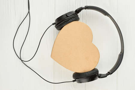 Headset and box in a shape of heart. Black headphones and beige heart-shaped gift box. Listen to your heart.の写真素材