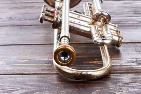 Trumpet on wooden background. Rusty trumpet on brown textured wood. Classical wind instrument.