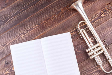 Trumpet and musical notes on wooden background. Notebook for musical notes and old trumpet with text space.の写真素材