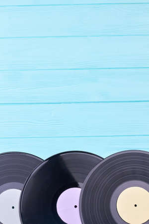 Vinyl discs with copy space on top. Set of vintage record albums on colored wooden surface. Retro media equipment.の写真素材