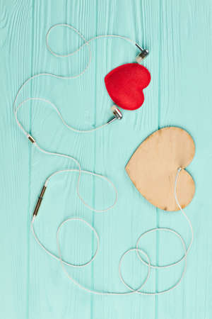 Earphones and hearts on wooden background. Headphones with two hearts on blue background, top view. Music and love.の写真素材
