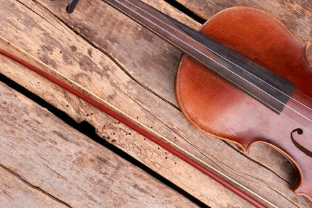 Violin and bow on wooden floor. Old violin and fiddle stick on rustic wooden planks. Musical equipment of orchestra.の写真素材