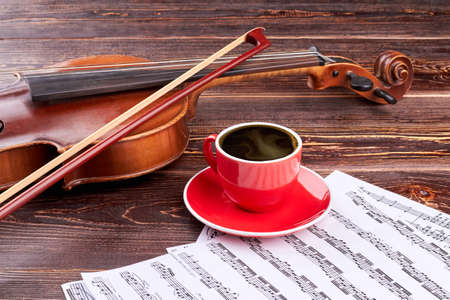 Violin and coffee cup on music sheets. Musical background with classical equipment. Music still life.の写真素材