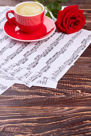 Musical notes, cup and red rose. Blank mug on musical sheets. Romantic musical background.の写真素材