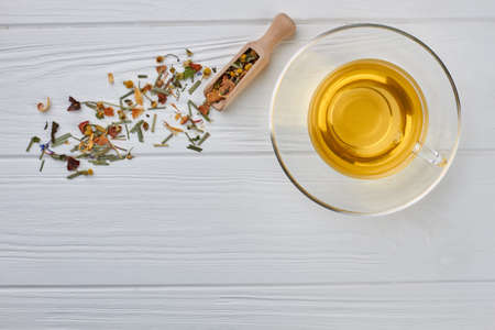Composition with a cup of tea on wooden background. Glass cup of herbal tea and wooden scoop with dried tea leaves. Space for text.の写真素材