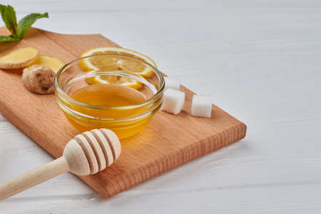 Honey, lemon and ginger on wooden cutting board. Ingredients for healthy warming drink.の写真素材