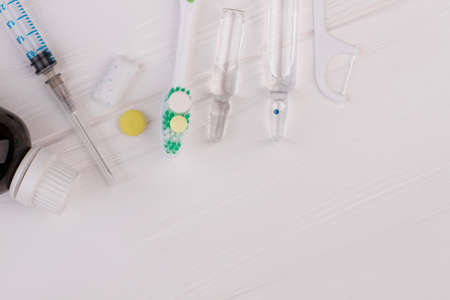 Toothbrush, ampoules with medicine and syringe. Dental care accessories on the white wooden background with copy space.の写真素材