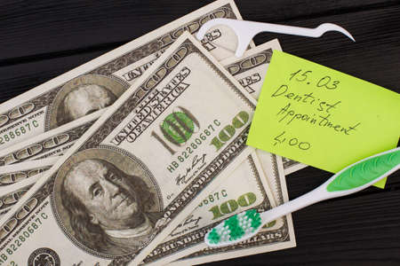 Note dentist appointment, toothbrush and money. American dollars, toothbrush and paper card with...