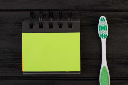Blank binder notebook and toothbrush. Green spiral notepad and tooth brush on black background. Flat lay composition.の写真素材