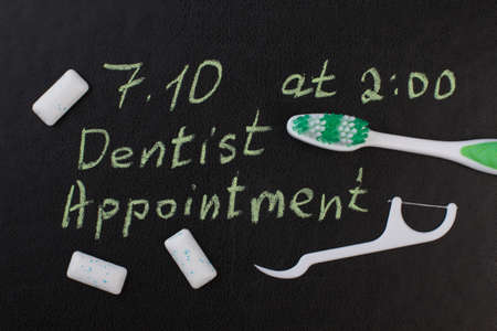 Toothbrush, dental floss and inscription dental appointment. Marked date and toothbrush to remind dentist appointment day in october.の写真素材