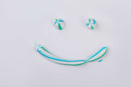 Toothpaste in a shape of face with smile. Smiling emoji face with colorful toothpaste. Tooth cleaning concept.の写真素材