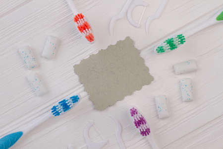 Different tools for dental care on white background. Toothbrushes, dental floss and blank paper card on white wooden background.の写真素材