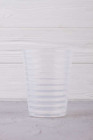 Empty plastic glass on white wooden background. Transparent plastic glass on wooden table.の写真素材