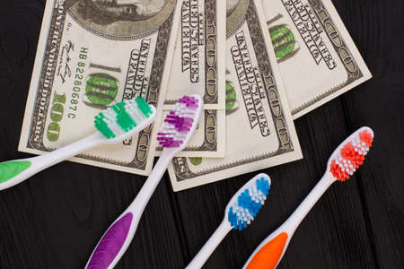 Toothbrush and money on black background. Dentistry, business and healthcare concept.の写真素材