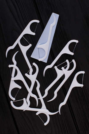 Group of dental floss toothpick on black wooden background. Plastic tools for teeth cleaning. Dental care concept.の写真素材