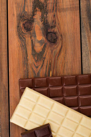 White and brown chocolate bars on wooden background. Chocolate pieces on rustic wooden boards. Top view and copy space.の写真素材