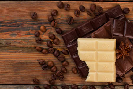 Chocolate bars and coffee beans on wooden background. Chocolate pieces and coffee beans on rustic wooden surface.の写真素材