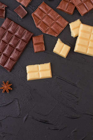 Different chocolate bars on black stone background. Various chocolate bars. Flat lay, copy space.の写真素材