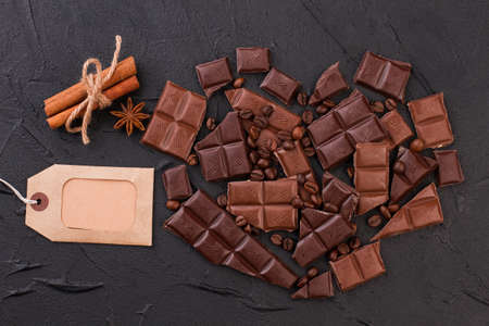 Heart shape made of chocolate and coffee beans. Shape of heart from chocolate pieces, cinnamon sticks and blank price tag.の写真素材