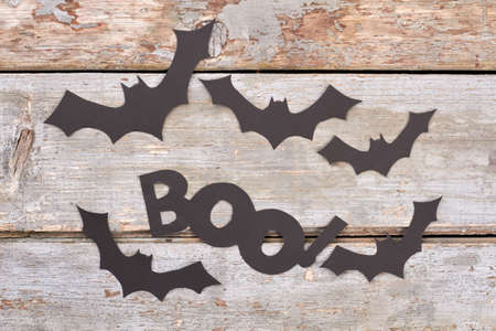 Black paper bats on wooden background. Halloween paper decorations. Happy Halloween concept.