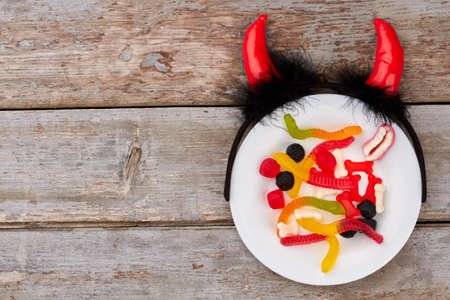 Table set for Halloween dinner. Halloween composition with sweets and devil headband with horns. Wooden background with copy space.の写真素材