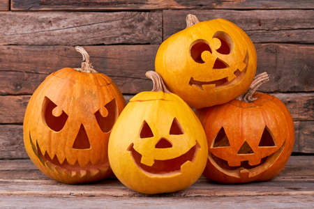 Funny Halloween pumpkins on wooden background. Group of pumpkins carved for Halloween party. Traditional holiday of fall.の写真素材