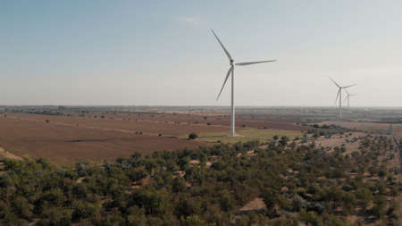Wind mills with blue sky lansdcape. Wind turbines and agricultural fields. Eco power energy concept.
