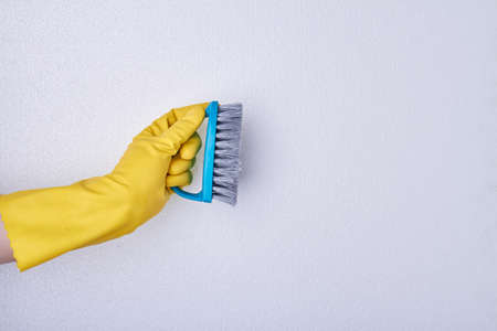 Hand in yellow glove holding brush for cleaning. Spring cleaning background.の写真素材
