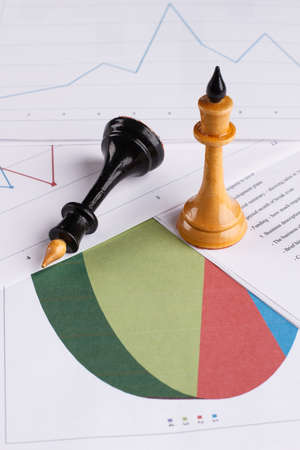 Chess figures in focus. Documents with charts. CV.