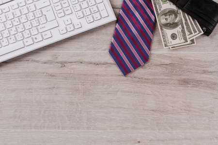 Keyboard on table close up. Striped tie and wallet full of money. Office workers salary.の写真素材