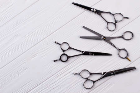 Set of barbers hair cutting scissors. Group of steel hairdressing scissors on white wooden...