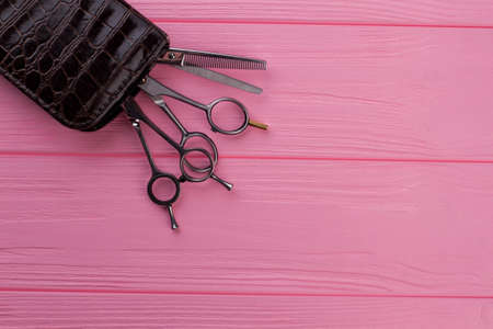 Professional barber scissors on pink background. Set of steel hairdresser scissors on color wood table. Space for text.の写真素材