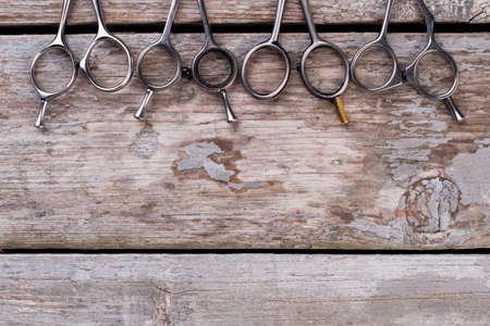 Set od hairdressing scissors on wooden boards. Steel barber scissors on rustic wooden background....
